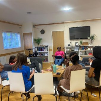 Picture of the founder with a group of ladies sitting down and discussing